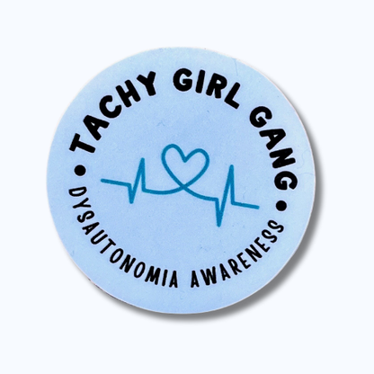 Round blue sticker with black text reading “Tachy Girl Gang” across the top and “Dysautonomia Awareness” across the bottom, featuring a light teal heart with a heartbeat line in the center.